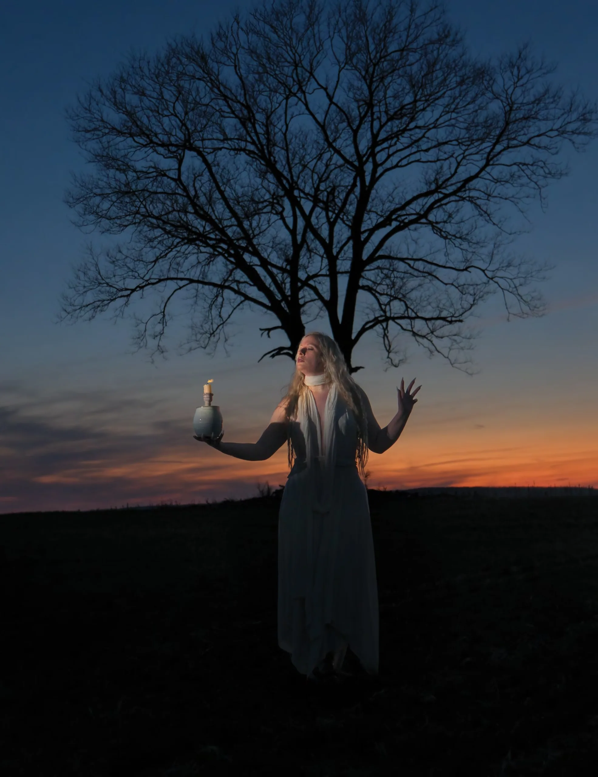 Rachael Platt_By_steve_parke_01 Winter Enchantment: Ceramicist Rachael Platt holding a lit manifesting jar under the full moon, surrounded by illuminated jars in a forest setting. Photography by steve parke